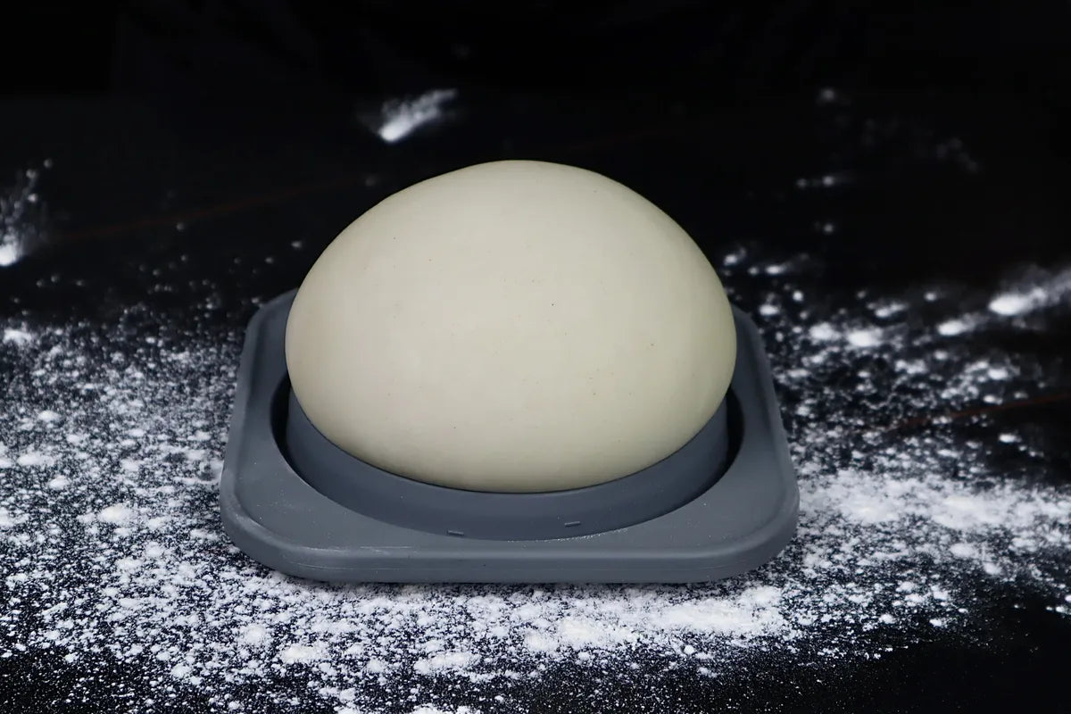 Close view of a relaxed 48-hour cold-fermented pizza dough ball in a KEVJES container