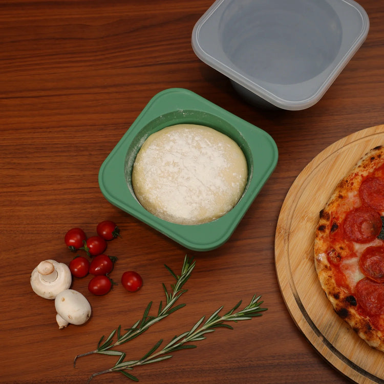 Pizza dough proofing in a green KEVJES silicone container beside a baked pizza